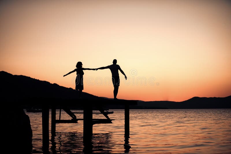 Couple in love on romantic date in evening at dock, copy space. Romance and love concept. Silhouette of sensual couple