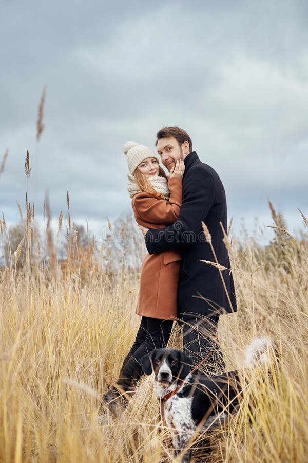 Couple in love on a warm autumn day walks in the Park with a cheerful dog Spaniel. Love and tenderness between a man and a woman royalty free stock photography Couple in love on a warm autumn day walks in the Park with a cheerful dog Spaniel. Love and tenderness between a man and a woman royalty free stock photography