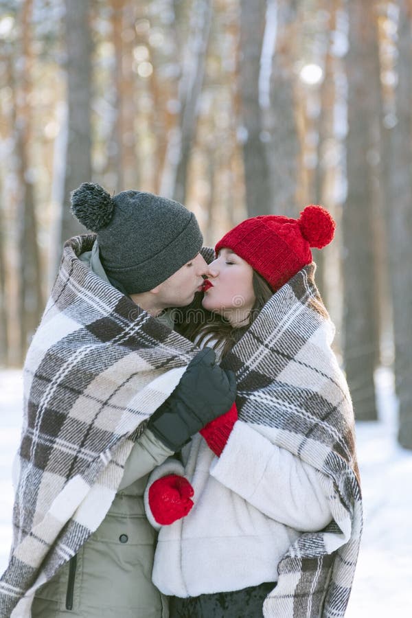 Couple In Love In Winter Park Hugs And Kisses Under Warm Blanket