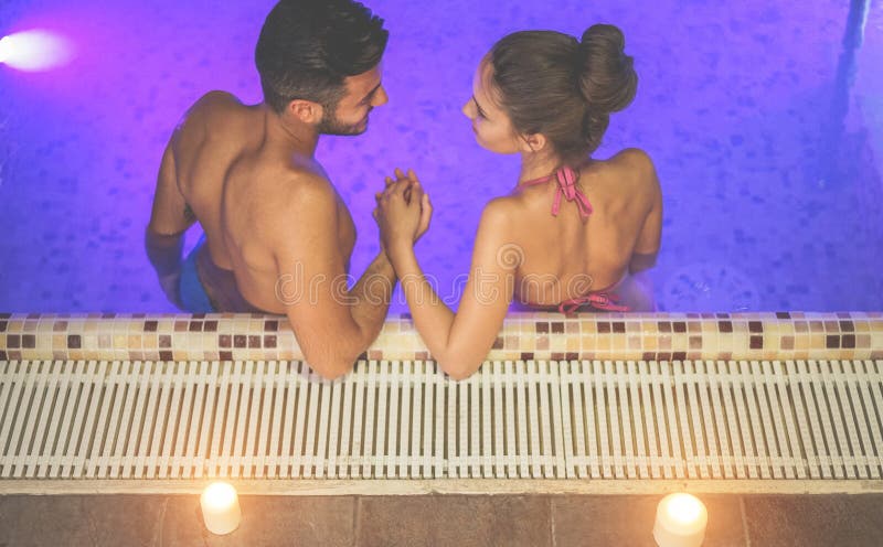 Couple of lovers having tender moments in spa swimming pool - Romantic love story on vacation resort hotel - Relationship concept