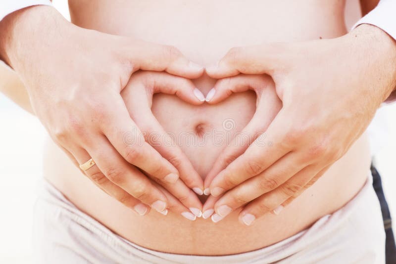 A couple making a heart shape on the pregnant belly