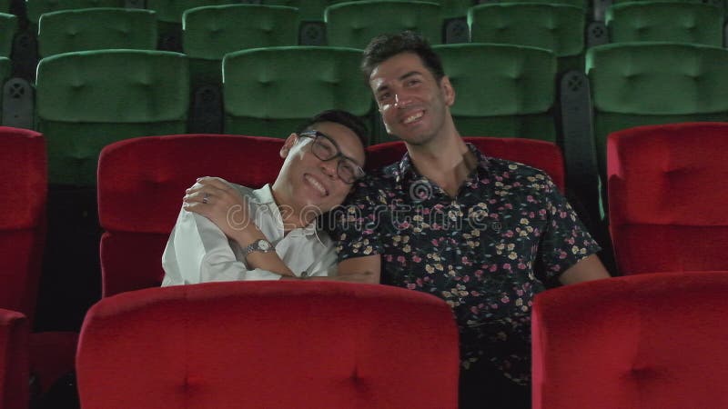 Couple of male lovers watch romantic cinema together at movie theaters.