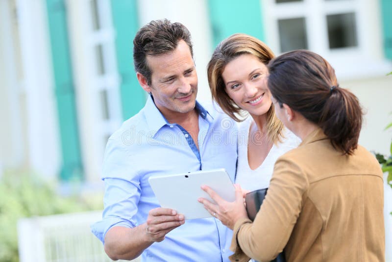 Couple meeting real-estate agent in front of their new home