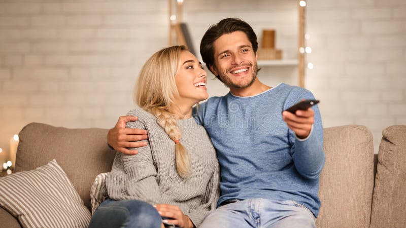 Couple mignon regarder la télévision profiter de l'atmosphère confortable à la maison images libres de droits