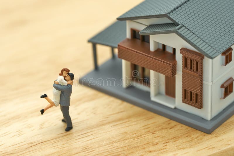 Couple Miniature 2 people standing model with house model make family Feel happy.as background real estate and family concept with