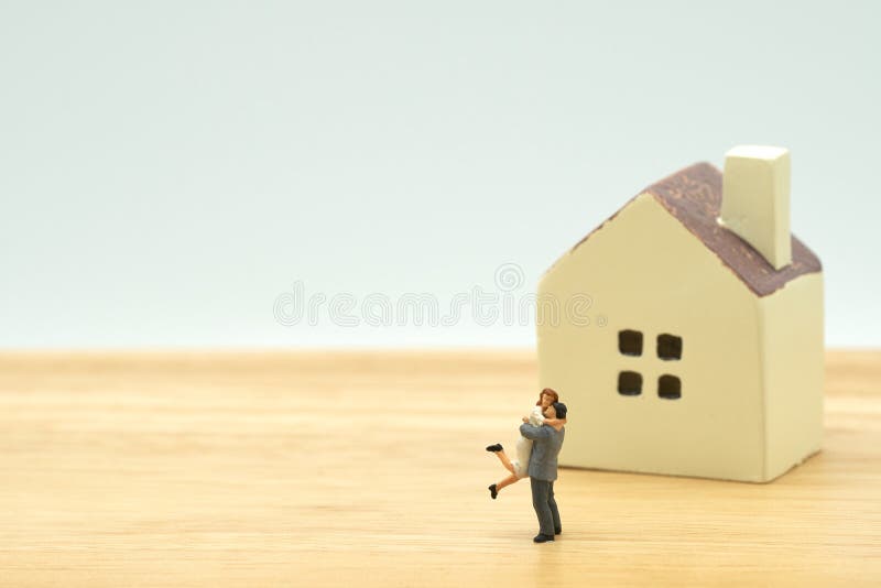 Couple Miniature 2 people standing model with house model make family Feel happy.as background real estate and family concept with