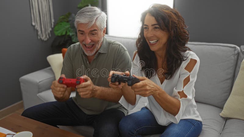 Couple moyen heureux jouer à des jeux vidéo ensemble dans un cadre confortable salon suggérant une interaction amusante à l'intéri images libres de droits