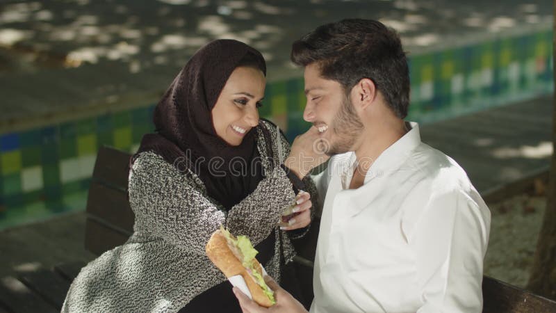 Couple musulman romantique assis sur un banc se nourrissant. clips vidéos