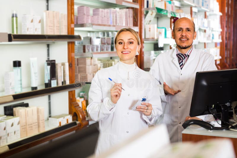 Couple of pharmacists standing with a cash desk in the pharmacy