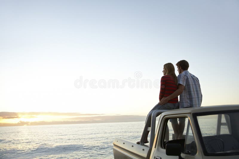 Couple On Pick-Up Truck Parked In Front Of Ocean stock images