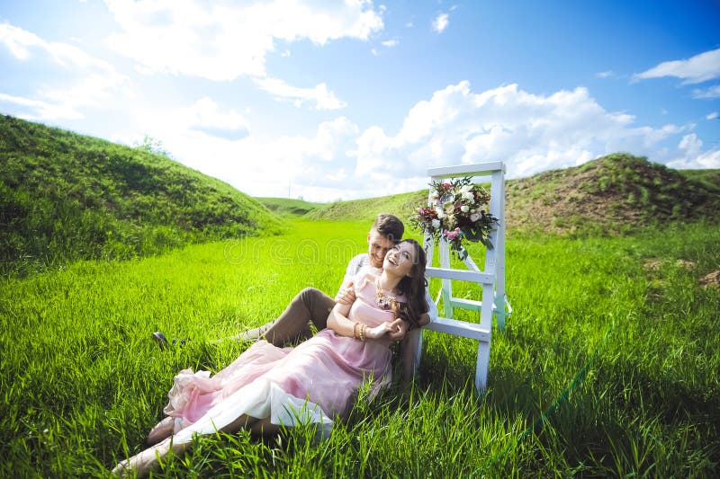 Couple portrait of a girl and guy looking for a wedding dress, a pink dress flying with a wreath of flowers on her head on a backg