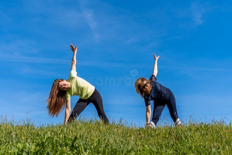 Couple Of Pretty Athletic Women Doing Gymnastics Exercises Outdoors