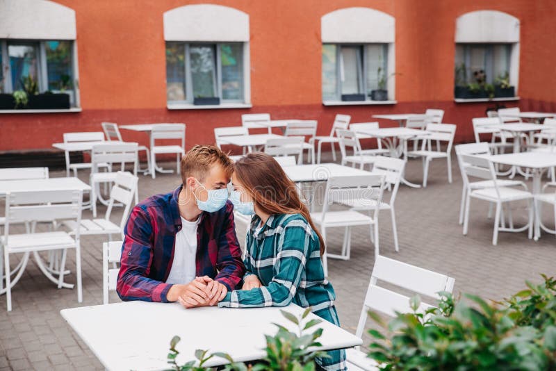 Couple In Protective Masks Sitting In Street Closed Cafe Stock Image
