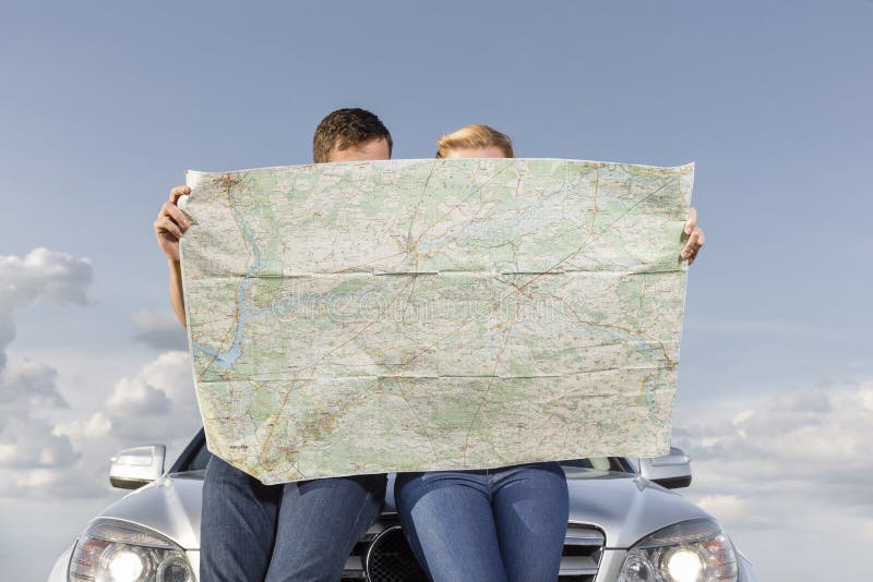 Couple reading map while leaning on car hood during road trip royalty free stock photos Couple reading map while leaning on car hood during road trip royalty free stock photos