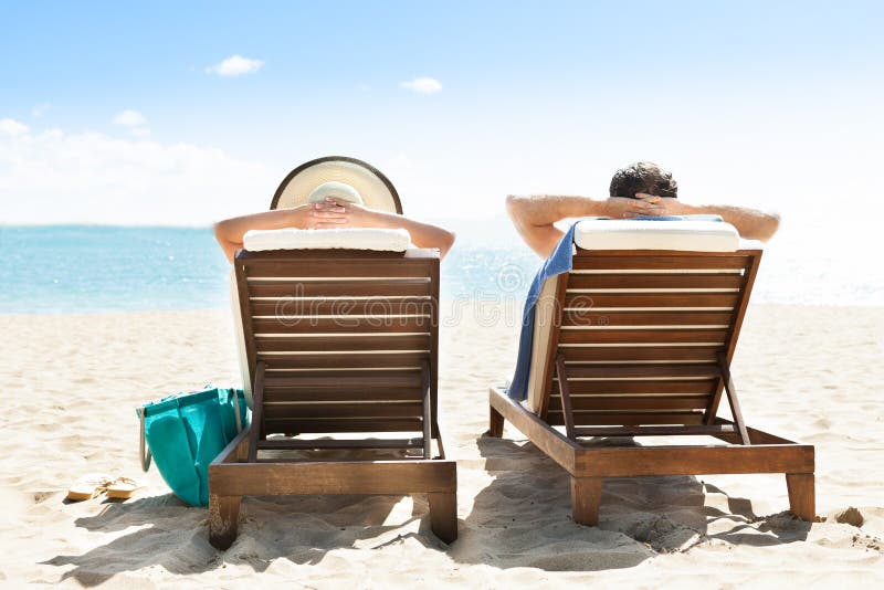 Couple relaxing on deck chairs at beach resort