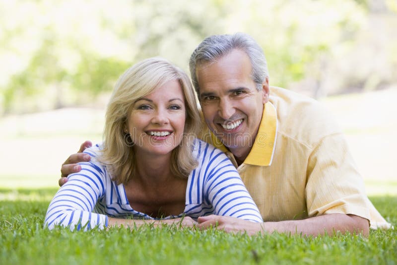 Couple relaxing outdoors in park smiling stock photo