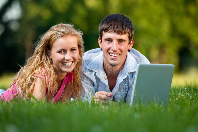 A couple relaxing in the park with a laptop