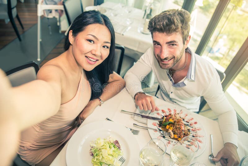 Couple of lovers in a restaurant and taking a picture - Romantic date in a classy restaurant at sunset - Two attractive friends having fun in a bistro bar. Couple of lovers in a restaurant and taking a picture - Romantic date in a classy restaurant at sunset - Two attractive friends having fun in a bistro bar