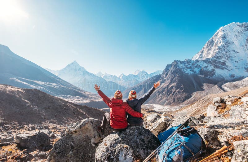 Couple rising arms rejoicing Everest Base Camp trekking route near Dughla 4620m. Backpackers left Backpacks and trekking poles and