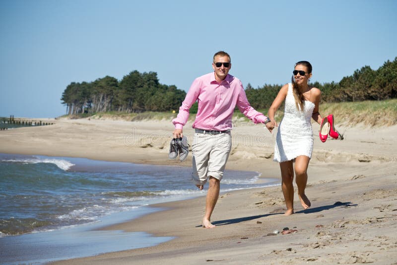 Couple running on beach by sea