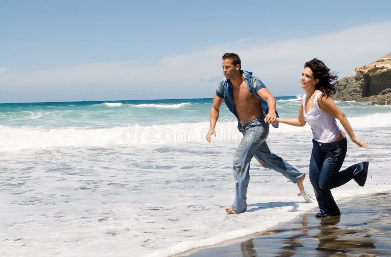 Couple running by the seaside in the beach