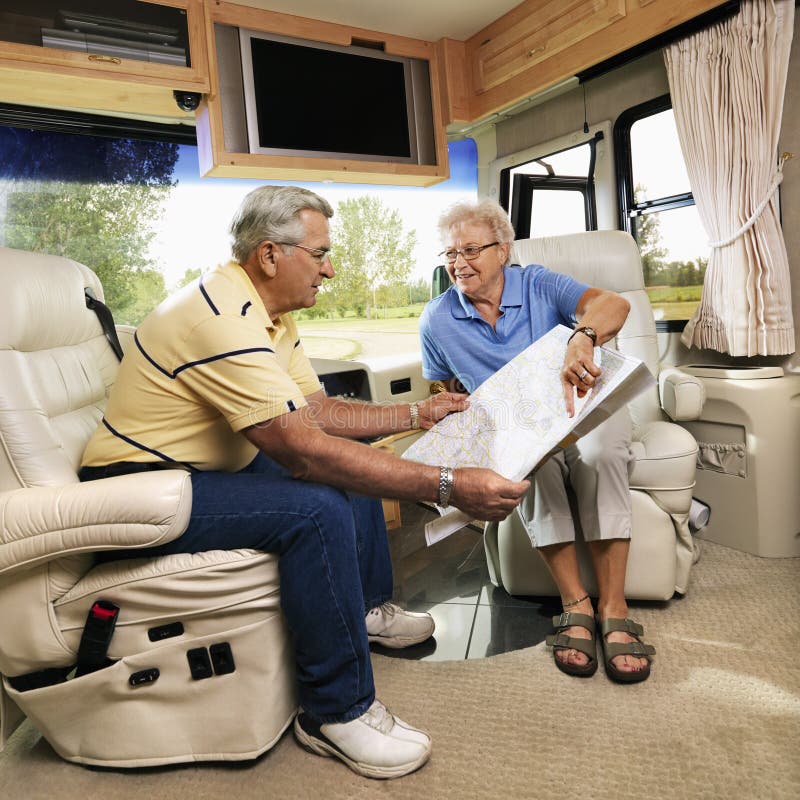 Senior couple sitting in RV looking at map and smiling. Senior couple sitting in RV looking at map and smiling.