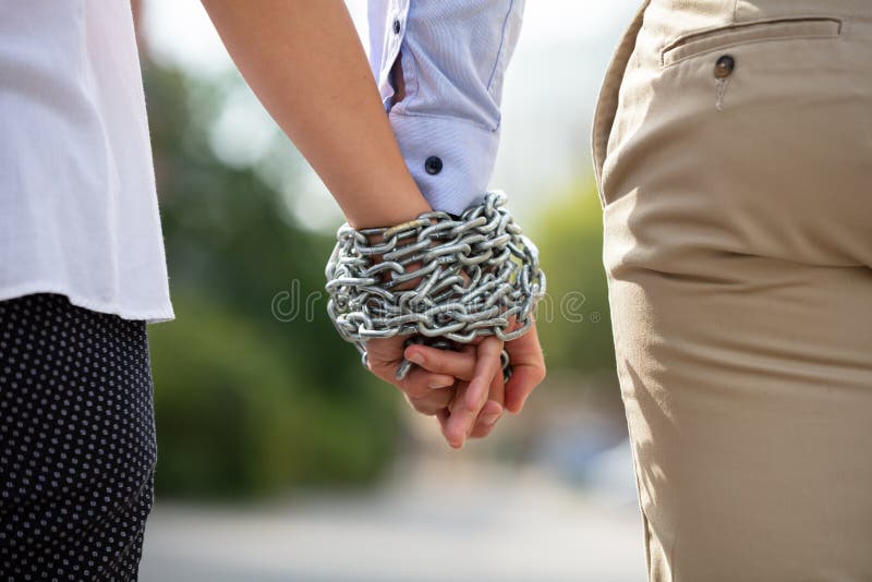 Couple`s Hand Tied With Metal Chain. Rear View Of Couple`s Hand Tied With Metal Chain At Outdoors