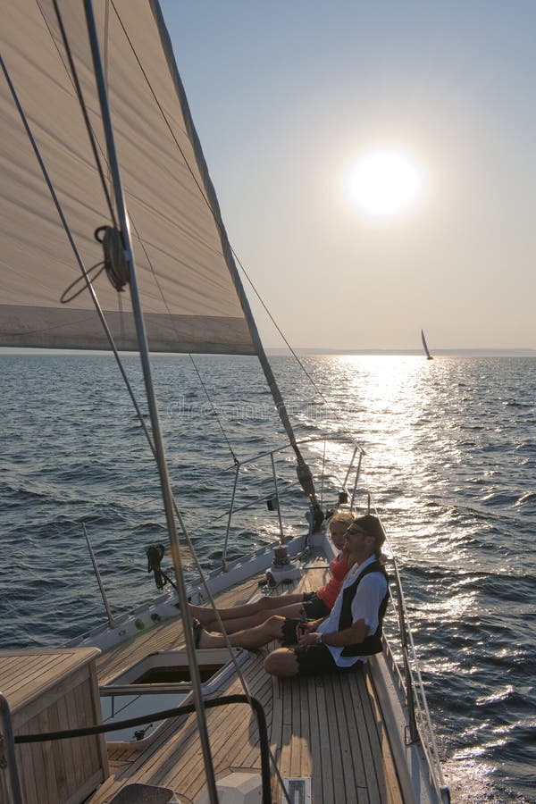 Paar entspannt auf dem deck der yacht mit Sonne im hintergrund.