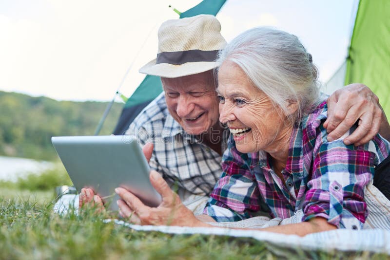 Couple of seniors using tablet computer while camping stock photo Couple of seniors using tablet computer while camping stock photo