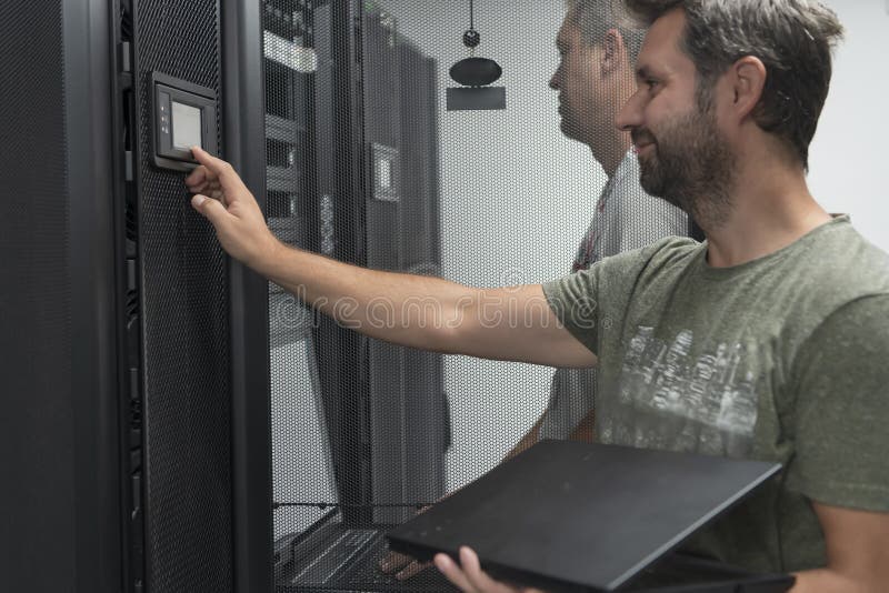 Technicians team updating hardware inspecting system performance in super computer server room or cryptocurrency mining stock photography