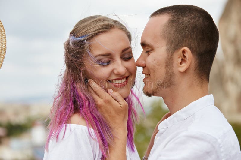 Couple shares a joyful moment as they smile at each other, surrounded by nature on a windy afternoon. vibrant colors of their hair stock photos