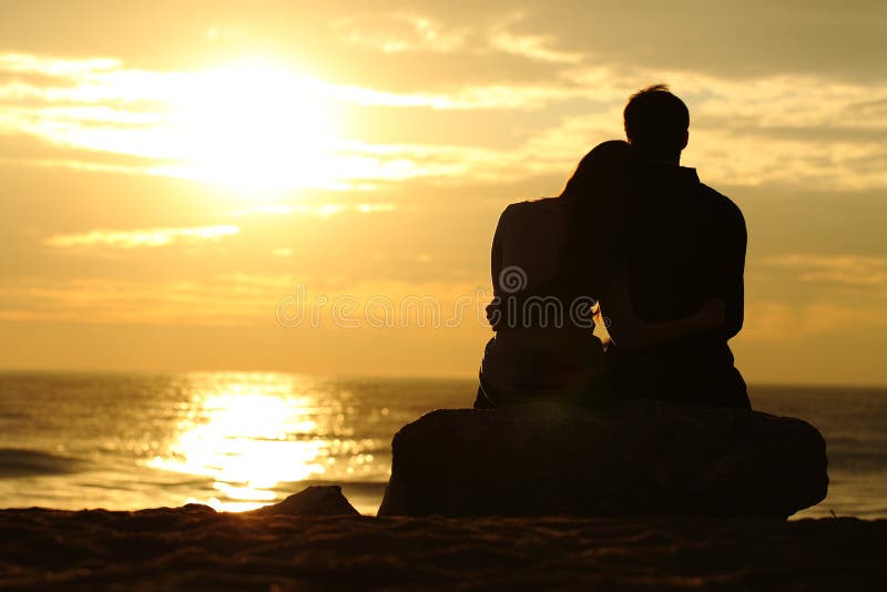 Couple silhouette watching sunset on the beach stock photography