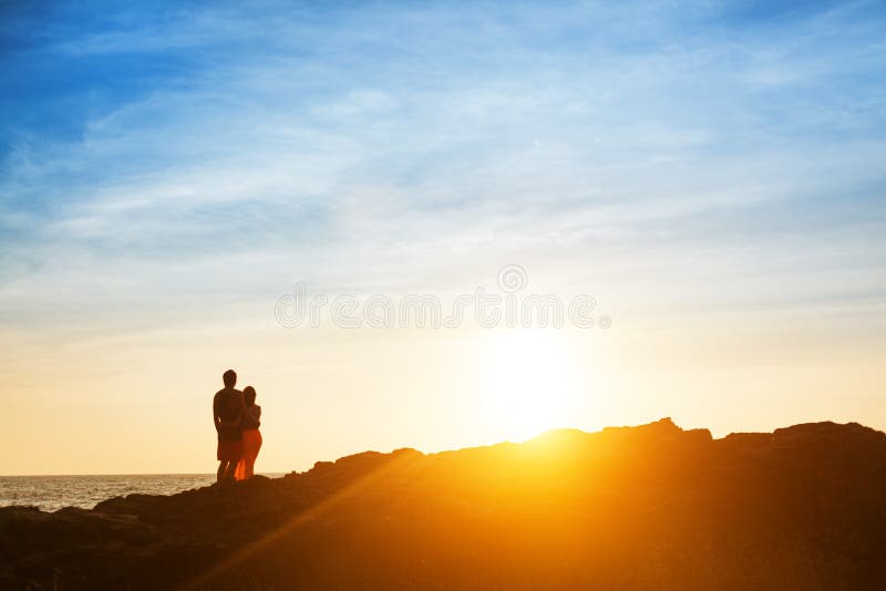 Couple sit on the rock and wait for sunset