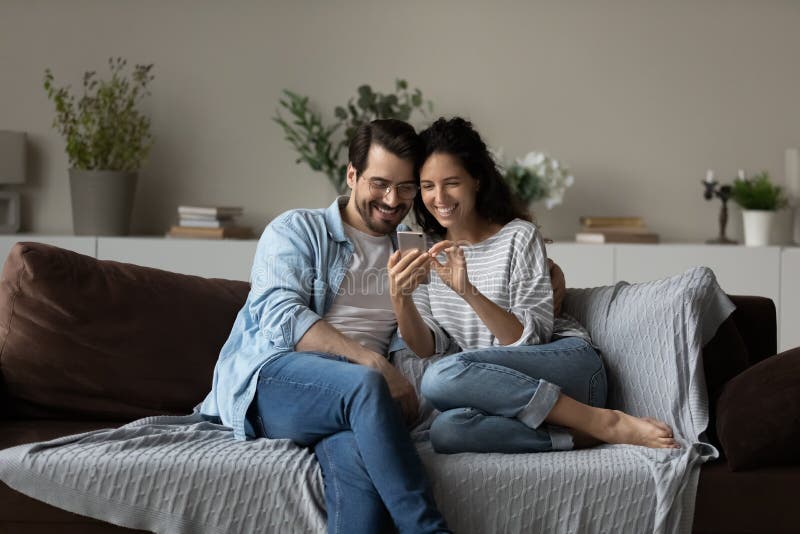 Couple Sit on Sofa Use Cell Phone Watch Video Online Stock Image