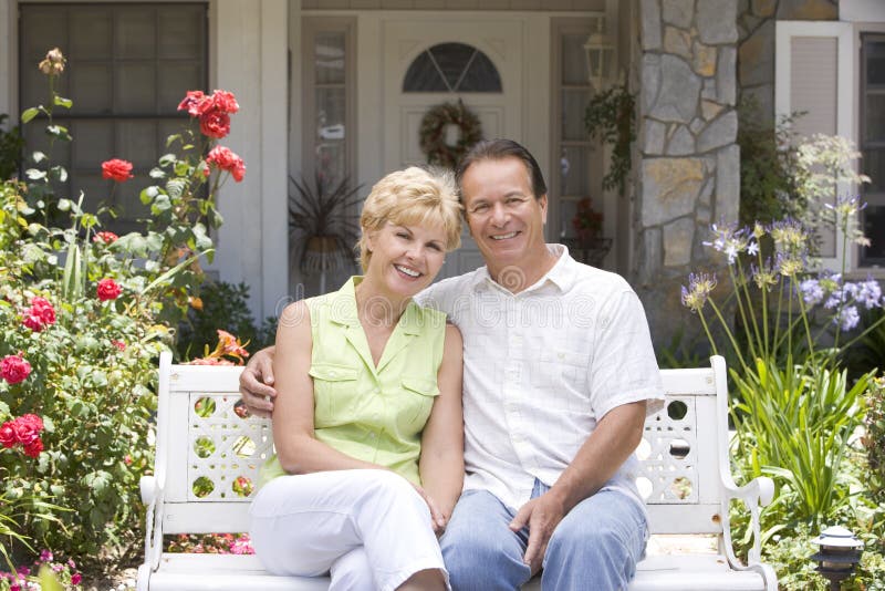 Couple Sitting On Bench Outside House stock photography