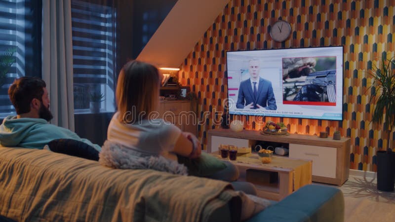 Couple on sofa watching military TV news