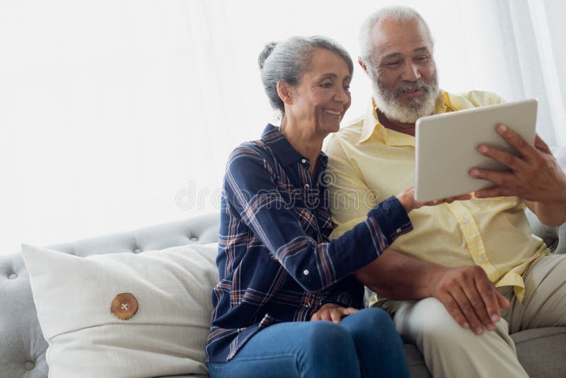 Couple sitting on couch while using a tablet royalty free stock photo