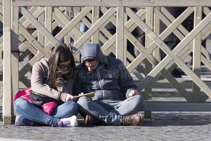 Couple sitting on the ground with a city guide stock photography Couple sitting on the ground with a city guide stock photography