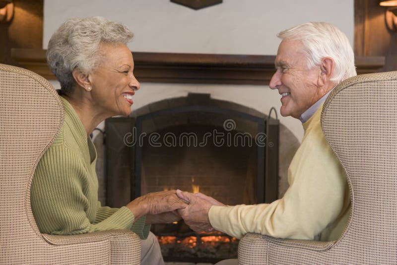 Couple sitting in living room by fireplace holding hands