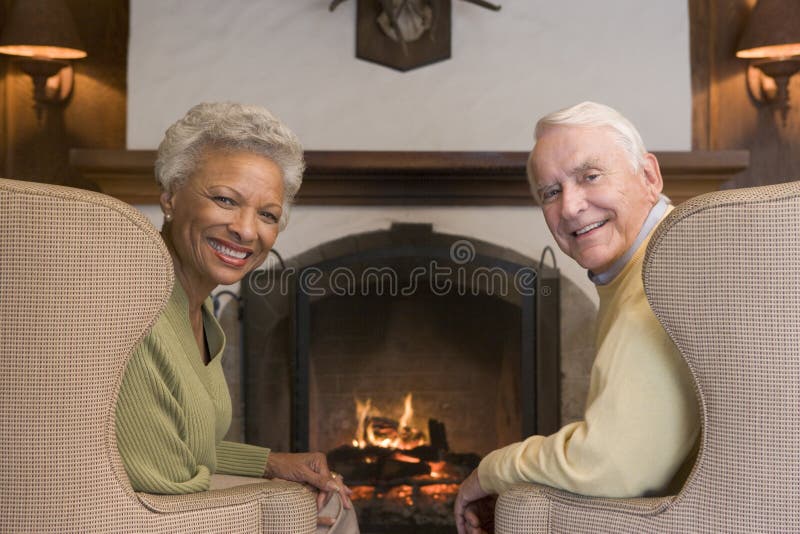 Couple sitting in living room by the fireplace smiling