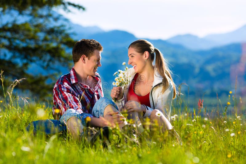 Happy Couple hiking taking a break sitting in alp meadow with mountain panorama. Happy Couple hiking taking a break sitting in alp meadow with mountain panorama