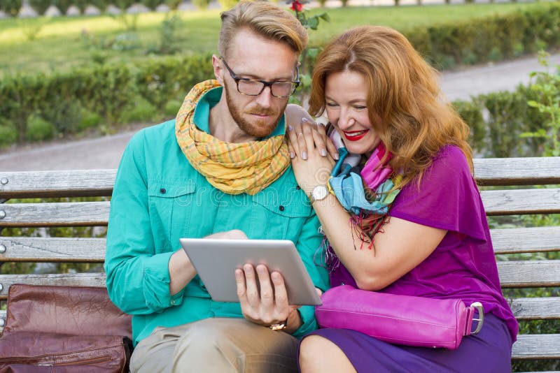 https://thumbs.dreamstime.com/b/couple-sitting-park-man-woman-looking-tablet-city-men-women-73813673.jpg