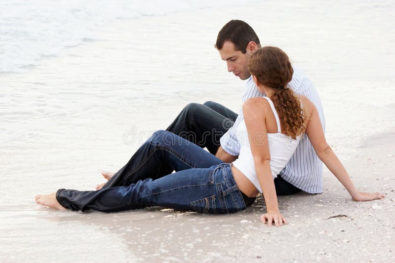 Couple sitting and talking in wet clothes at beach