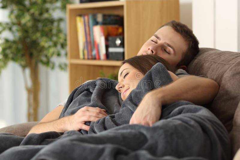 Portrait of a relaxed couple embracing and sleeping together on a couch at home lying on a couch in the living room at home. Portrait of a relaxed couple embracing and sleeping together on a couch at home lying on a couch in the living room at home