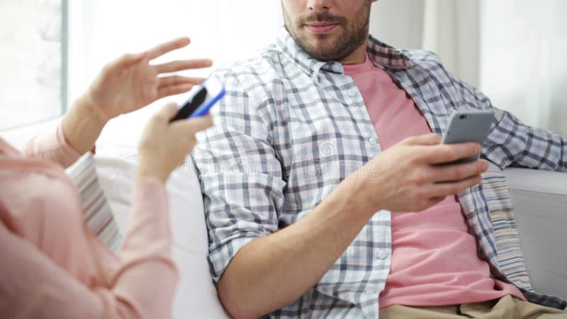 Couple with smartphones texting at home