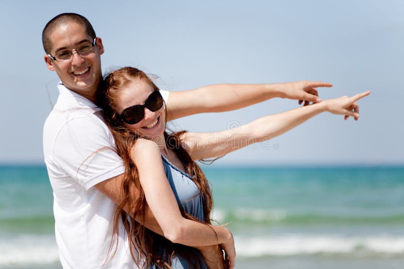 Couple smiling and pointing at the sea
