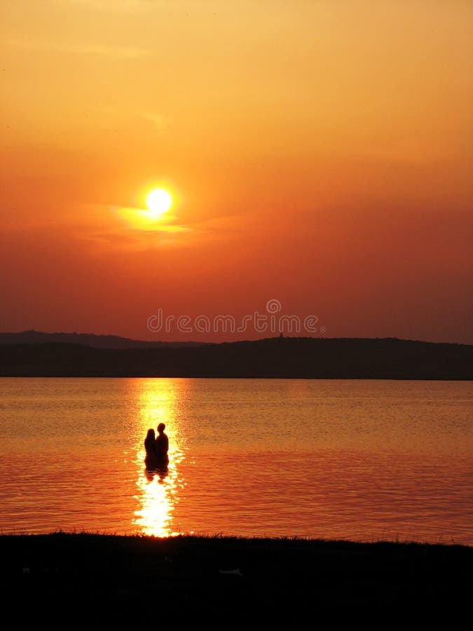 Couple standing in the water at sunset