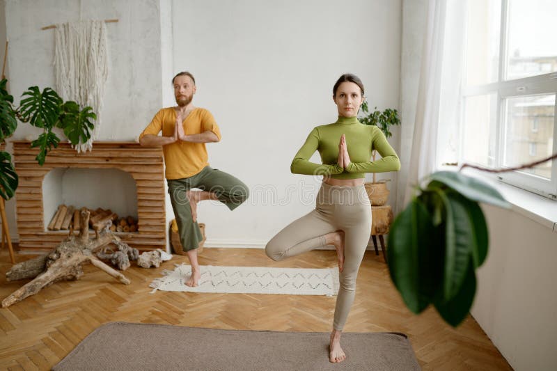 Couple standing in yoga vrikshasana tree pose, cropped shot with selective focus royalty free stock photos