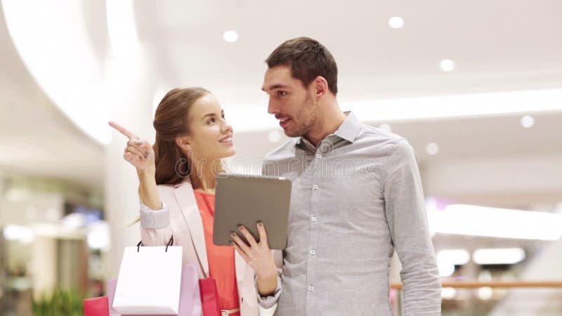 Couple with tablet pc and shopping bags in mall