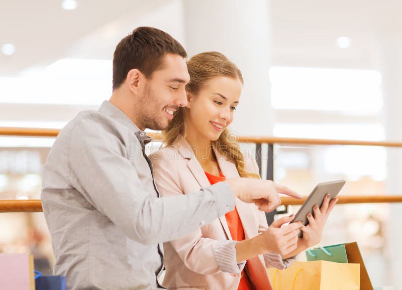 Couple with tablet pc and shopping bags in mall